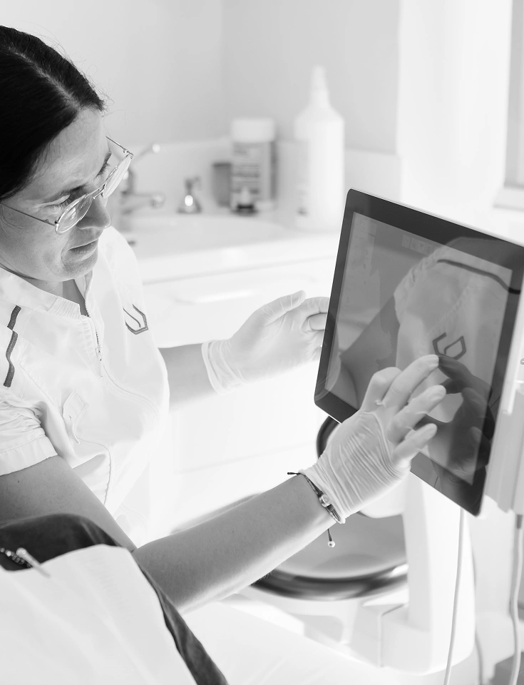 Odontòloga de Junyent Estudi Dental analitzant en pantalla tàctil un escàner digital 3D de la boca d'un pacient.